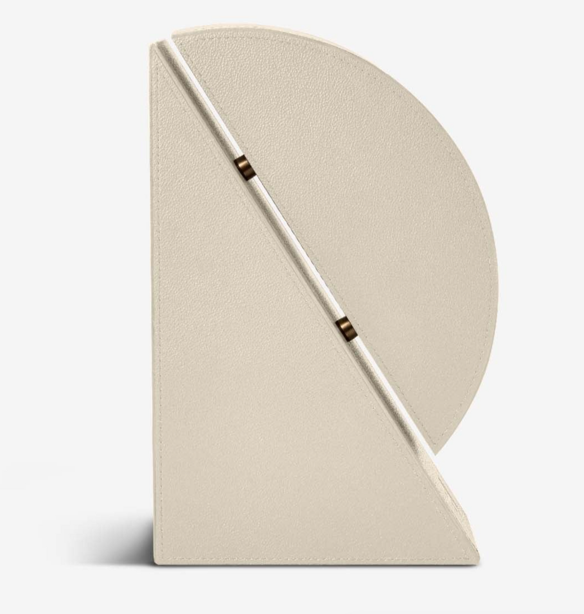 The Assouline Cubist Bookend - Right in Stone Leather showcases a geometric, cream-toned design with a pebbled leather texture, featuring a semi-circular upper section and an angled diagonal closure accented with metallic details. It stands upright against a plain white background.