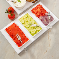The Bright White Brunch Board by Inspired Generations is artfully arranged with rectangular dishes filled with sliced tomatoes, cucumbers, red onions, and a vibrant red spread, each served with coordinating forks. Set on a white tray atop a marble surface—with two whole tomatoes on the side for extra freshness—this stylish serving board is perfect for an organized brunch.