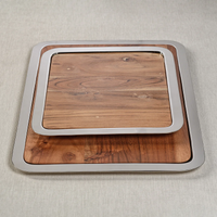 Two rectangular Braxton Wood Serving Trays by Zodax, featuring gleaming silver edges, are stacked together on a light gray surface—with the smaller tray nestled inside the larger—for a versatile 2-in-1 set perfect for serving appetizers or presenting a stylish charcuterie board.