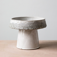 A ceramic pedestal bowl with a wide, shallow dish, narrow base, and glossy white glaze with speckled gray edges—ideal for pairing with the Cindy Froth Vase by Kalya OD Studio as an artisan home decor accent.