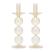 The Kim Seybert Iris Candlestick Holder Set of 2 features elegant hand-blown glass, each with three stacked ribbed spheres and scalloped base and top in a light beige or champagne hue.