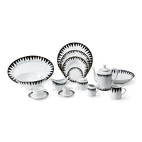The Molecot Punk Dinnerware set features white porcelain dishes, cups, and a teapot with bold black triangular edge patterns, all arranged neatly on a white surface.
