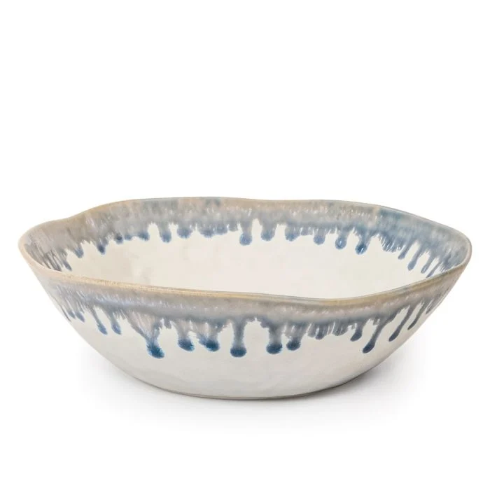 The Simon Pearce Burlington Dinnerware Pool handmade ceramic bowl features an uneven rim, white glaze with a blue drip pattern—an eye-catching, unique piece to enhance your Burlington dinnerware collection.