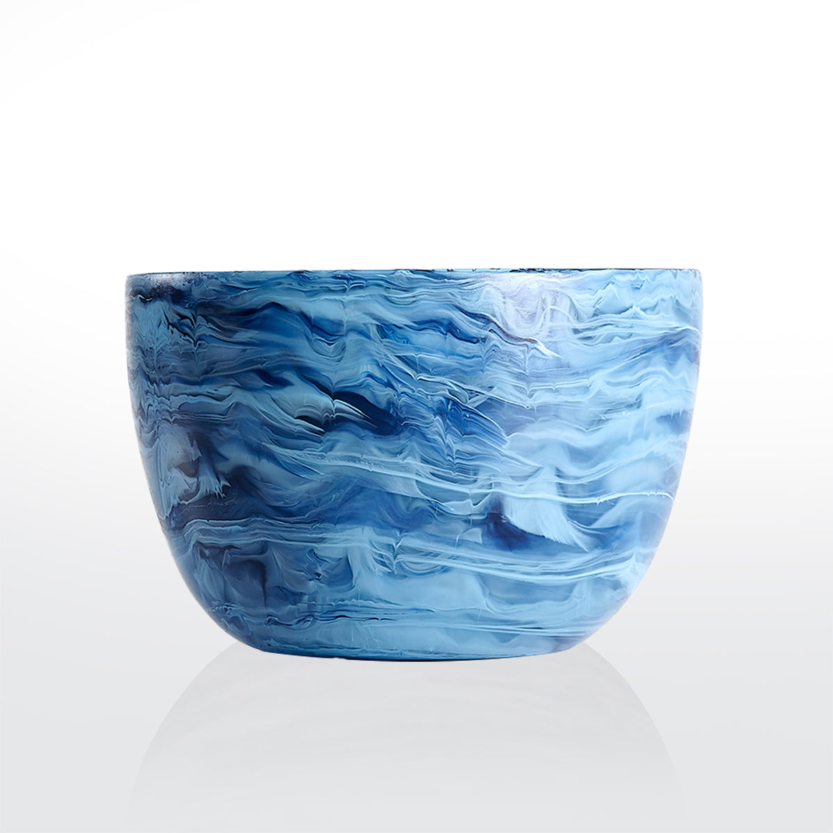 The Nashi Home Swirl Colored Resin Deep Bowl features a marbled blue and white pattern, reminiscent of swirling waves. Made from shatterproof resin, this stylish bowl is both beautiful and durable, shown against a plain white background.