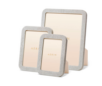 Three elegant Modern Shagreen Frame Dove photo frames by Aerin in light gray with embossed texture are shown upright on a white background, each featuring a beige Aerin-labeled insert.