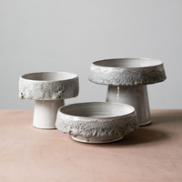 Three white textured ceramic pedestals of varying sizes stand against a light gray background, perfect for displaying artisan home decor such as the Cindy Froth Vase by Kalya OD Studio or your favorite stoneware vase.