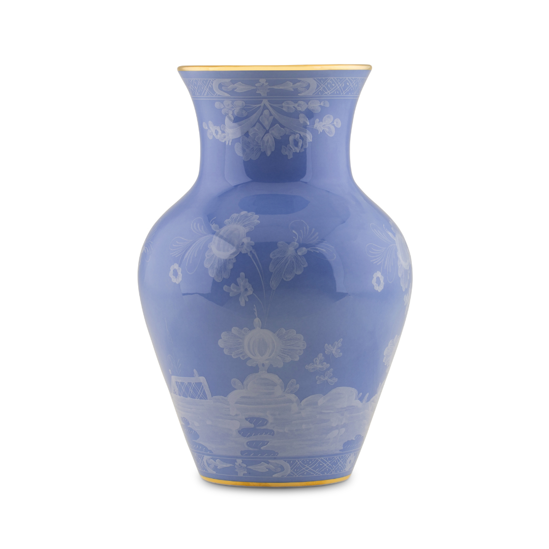 The Oriente Italiano Pervinca by Ginori 1735 is a glossy, light blue ceramic vase with a wide round body, narrow neck, white floral patterns, and luxurious 24-karat gold trim on the rim and base.