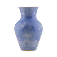 The Oriente Italiano Pervinca by Ginori 1735 is a glossy, light blue ceramic vase with a wide round body, narrow neck, white floral patterns, and luxurious 24-karat gold trim on the rim and base.