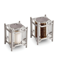 The Han Spice Jewels Set Salt & Pepper by L'Objet features square shakers with metal frames, 24k gold-plated tops, and clear bodies to display contents—elegantly packaged in a luxury gift box.