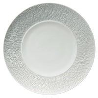 The Raynaud Mineral Dinnerware Glazed White plate, inspired by French design, displays a textured patterned rim and smooth center, shown from above on a plain background.
