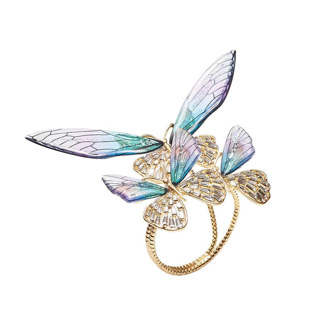 The Kim Seybert Flutter Napkin Ring Set of 4 in Lilac & Periwinkle features jeweled butterflies with pastel wings and gold accents, adding a delicate, elegant touch to any table setting.