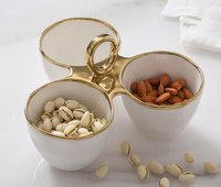 The PAMPA BAY Golden Handle 3 Section Server displays pistachios and almonds on a white surface, with scattered pistachios and a folded napkin in the background.