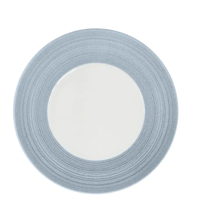 A round ceramic plate from JL Coquet’s Hemisphere Dinnerware Storm Blue collection, showcasing a wide, textured storm blue rim with engraved porcelain-inspired detailing and a smooth white center, viewed from above on a white background.