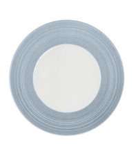 A round ceramic plate from JL Coquet’s Hemisphere Dinnerware Storm Blue collection, showcasing a wide, textured storm blue rim with engraved porcelain-inspired detailing and a smooth white center, viewed from above on a white background.
