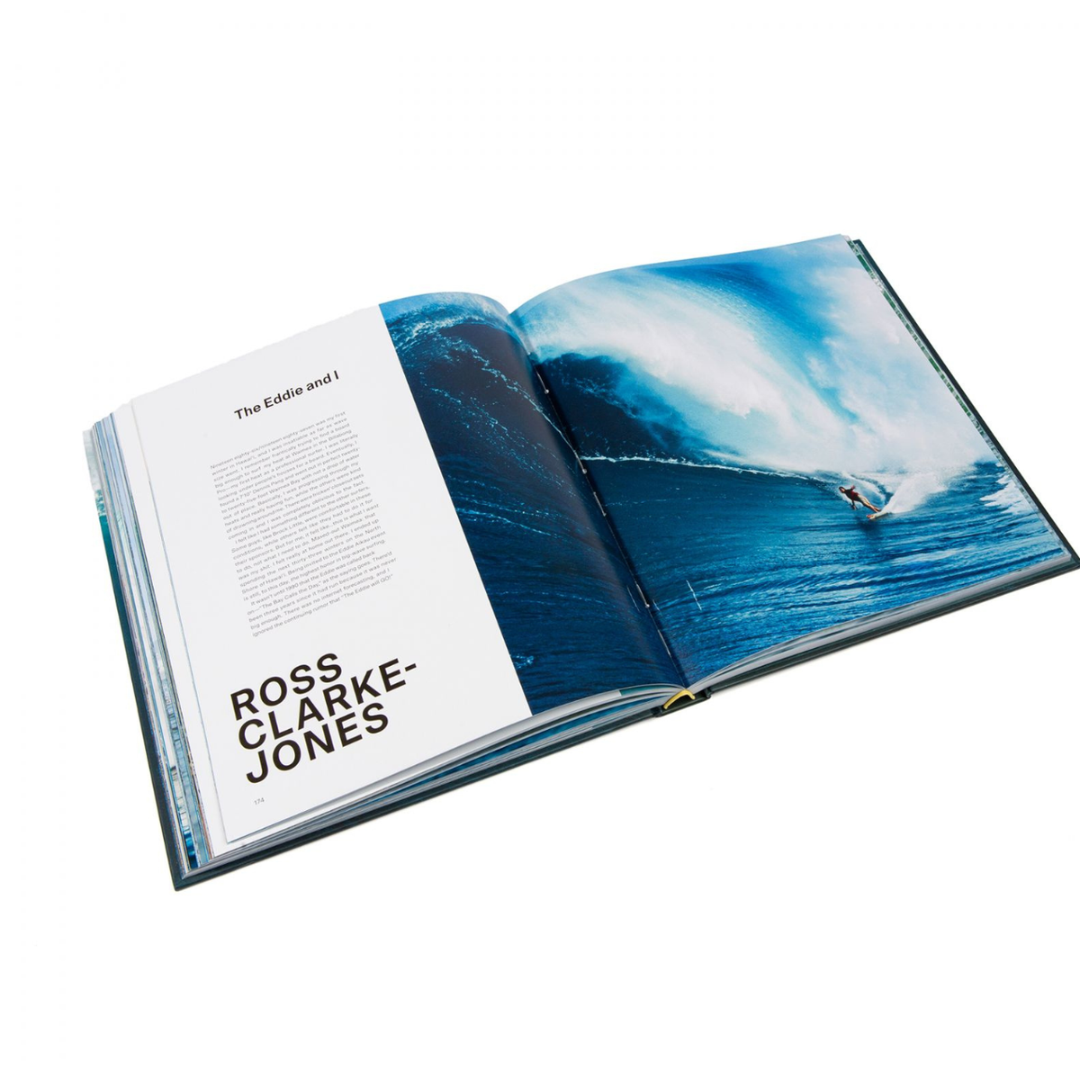 An open "Big Wave Surfer" book by Rizzoli shows Ross Clarke-Jones on the left page with text, and a surfer riding a massive blue and white ocean wave on the right, capturing the excitement of big wave surfing.
