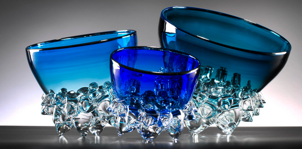 The Axiom Thorn Vessel Opal Blue - Medium 9" is an elegant glass bowl with a smooth, rounded shape and a textured base reminiscent of clear crystals, displayed against a neutral background.