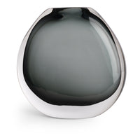 The Nellie Vase by FlowDecor Inc. is a modern, round glass vase with a wide, flat shape and smokey gray tinted glass that fades from dark to light. Its glossy finish makes it a standout piece for contemporary home decor.