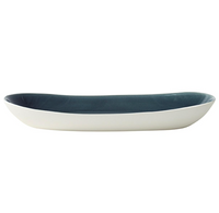 The Maguelone Outremer Dark Blue serving platter by Jars - Rosenthal features an oval shape and Mediterranean-inspired design with a white exterior and dark blue interior. Shown from the side on a plain white background. Dishwasher safe for easy care.
