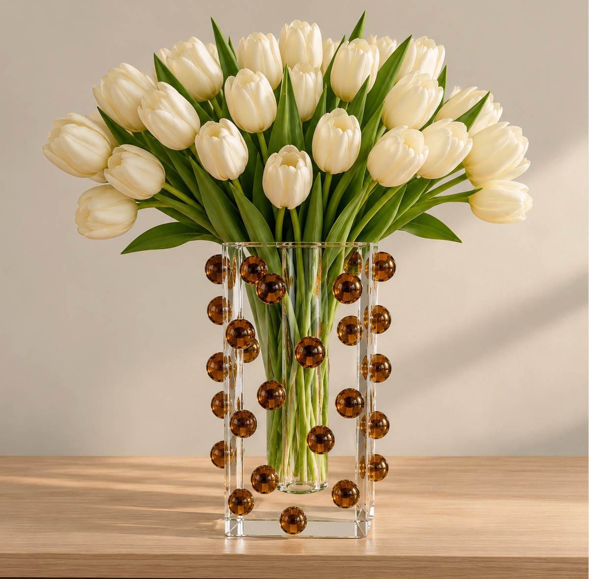 A bouquet of white tulips in a clear square Tizo Scattered Balls Vase Brown decorated with small brown spheres.