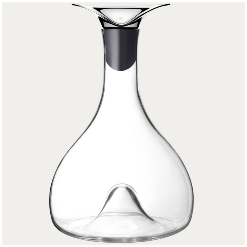 The Georg Jensen Wine & Bar Carafe features clear glass, a modern flared metal spout, and a wide base with an upward-pointing center indentation designed for optimal wine aeration.