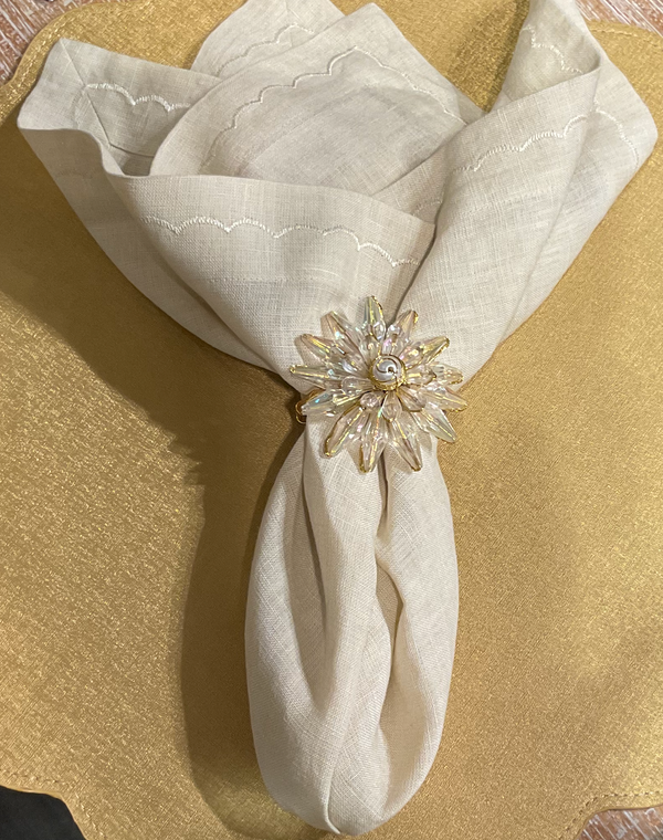 The Deborah Rhodes Signature Washed Linen Napkin Set of 4 in Ivory, paired with a starburst napkin ring featuring clear crystals and a pearl center, adds an elegant touch to your table setting.