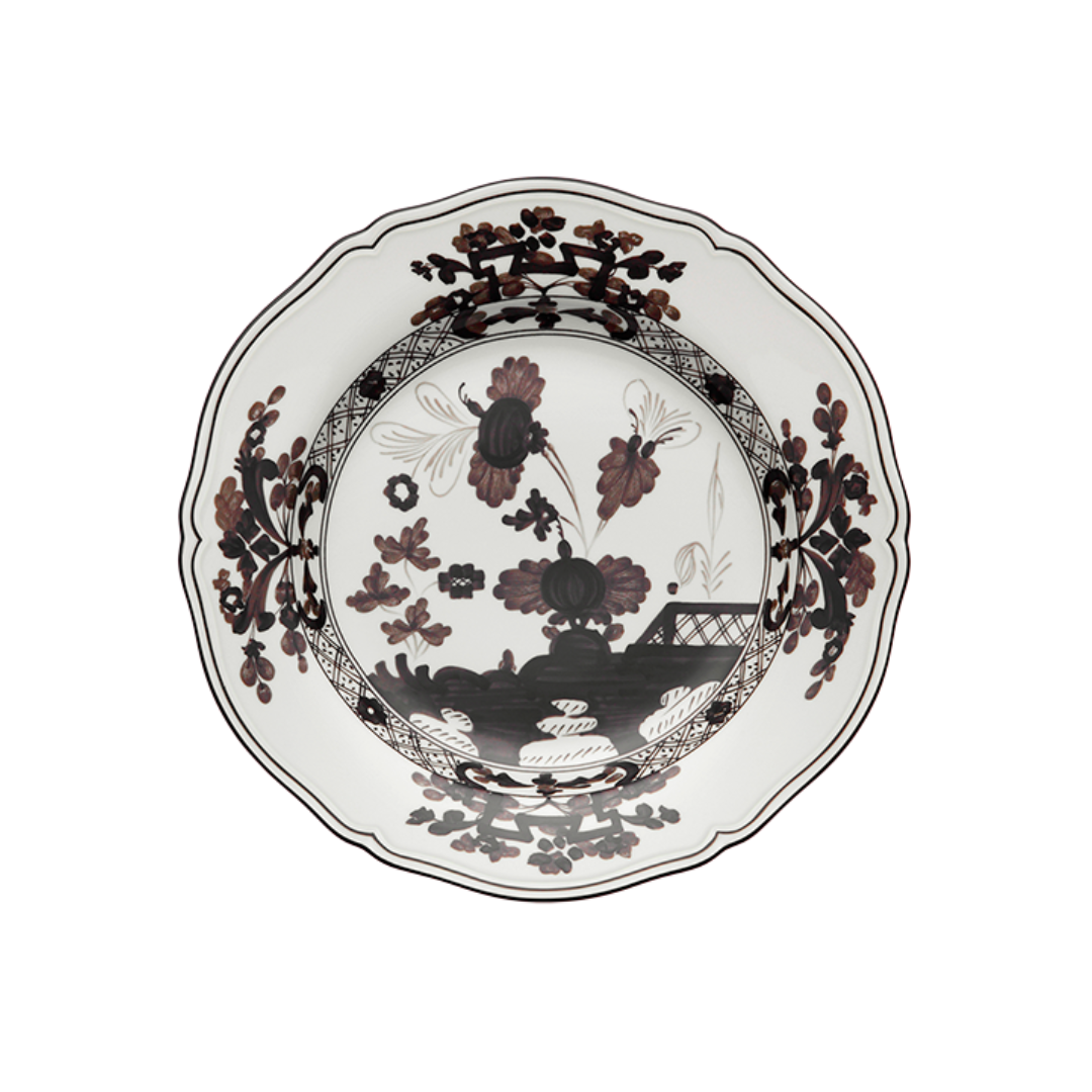 The Oriente Italiano Dinnerware Albus by Ginori 1735 is a decorative Italian porcelain plate with a scalloped edge, showcasing an intricate black and brown floral and landscape design on white for timeless elegance.
