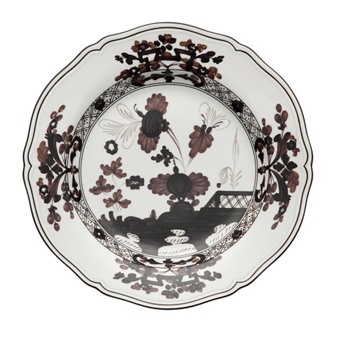 The Oriente Italiano Dinnerware Albus by Ginori 1735 is a white porcelain plate with scalloped edges, adorned with black and maroon floral and foliage patterns and intricate border designs.