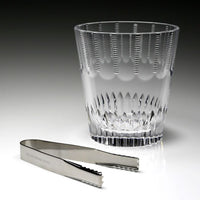 The Karen Ice Bucket by William Yeoward features a crystal design with vertical cuts and includes silver ice tongs engraved with the brand—an elegant accessory to enhance your bar setup.