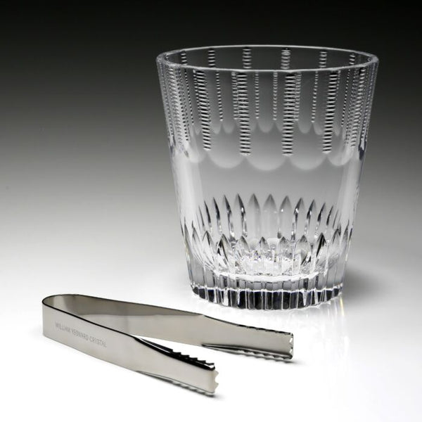 The Karen Ice Bucket by William Yeoward features a crystal design with vertical cuts and includes silver ice tongs engraved with the brand—an elegant accessory to enhance your bar setup.