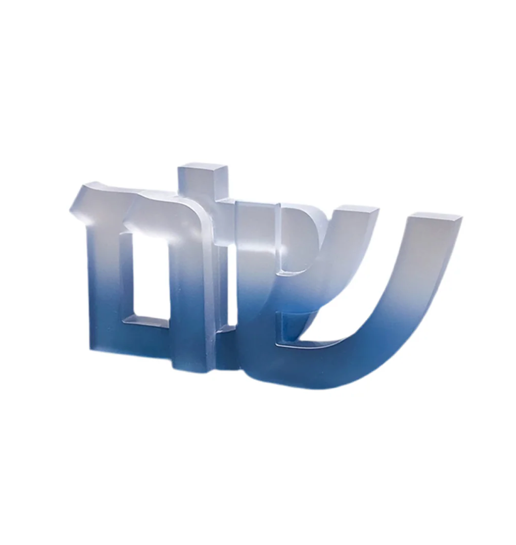 The CDMX / BRUCI Shalom Sculpture is a shiny, metallic piece with a silver-to-blue gradient, elegantly representing the Hebrew word "shalom" as stylish Jewish home decor against a simple white background.