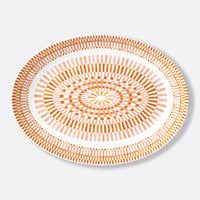The Bernardaud Terra Rosa Dinnerware is a round white plate adorned with intricate orange and light pink geometric patterns, showcasing elegance and artistry. Made in Limoges, France.
