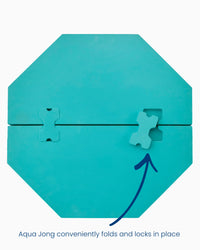 The Mahjong Aqua Pool Mat by Oh My Mahjong is a turquoise octagonal float, shown folded with two interlocking pieces and a blue arrow pointing to the lock. Text: “Conveniently folds and locks in place.”.