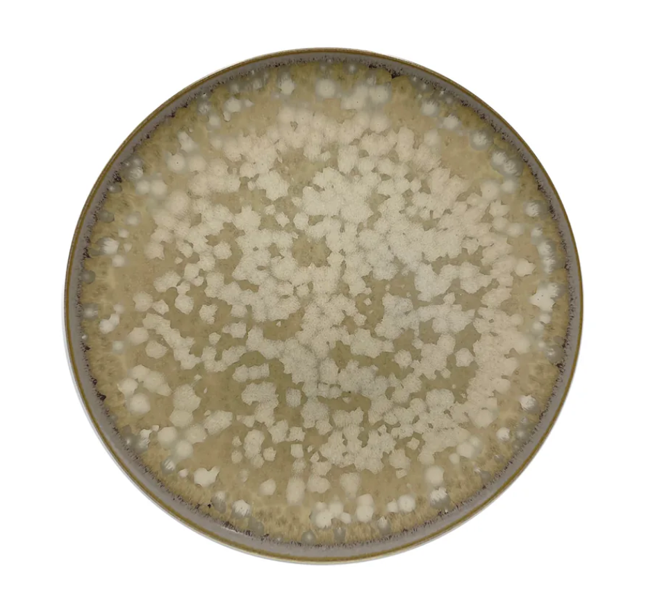 The Basmati Agora Dinnerware plate by Jaune De Chrome is a round ceramic piece with a mottled beige and cream glaze, speckled irregular pattern, and a darker rim, shown from above on a white background.