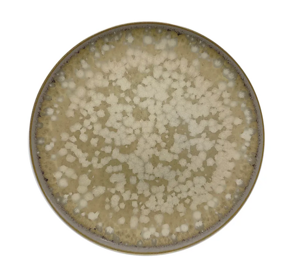 The Basmati Agora Dinnerware plate by Jaune De Chrome is a round ceramic piece with a mottled beige and cream glaze, speckled irregular pattern, and a darker rim, shown from above on a white background.