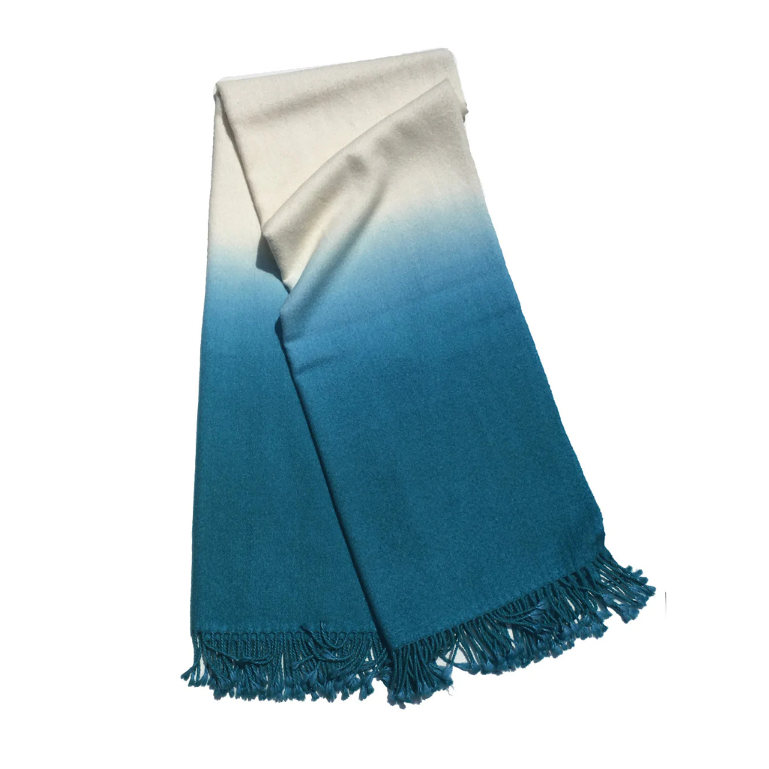 The Johanna Howard Dip Dye Throw features a white-to-teal blue ombré gradient and fringed edges.