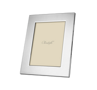 The America Stainless Steel Frame by Christofle is a silver rectangular picture frame with a subtle vertical line pattern, Art Deco-inspired from the America Collection, and features a beige Christofle-branded placeholder.