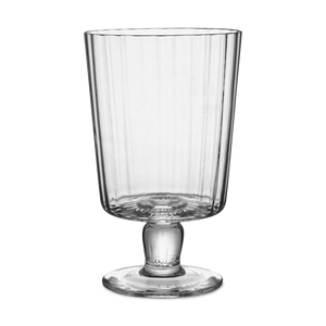The Lando Pleat Glassware by MATCH features a tall, clear, mouth-blown glass with vertical ridges, a flared rim, and a footed base, inspired by antique Italian designs.