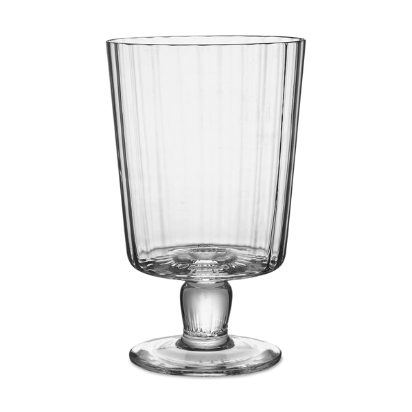 The Lando Pleat Glassware by MATCH features a tall, clear, mouth-blown glass with vertical ridges, a flared rim, and a footed base, inspired by antique Italian designs.