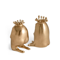 Two gold, frog-like figures with crowns—Haas King & Queen Candlesticks by L'Objet—sit on a white background, each facing opposite directions. These luxury collectibles make an imaginative gift or decorative accent.