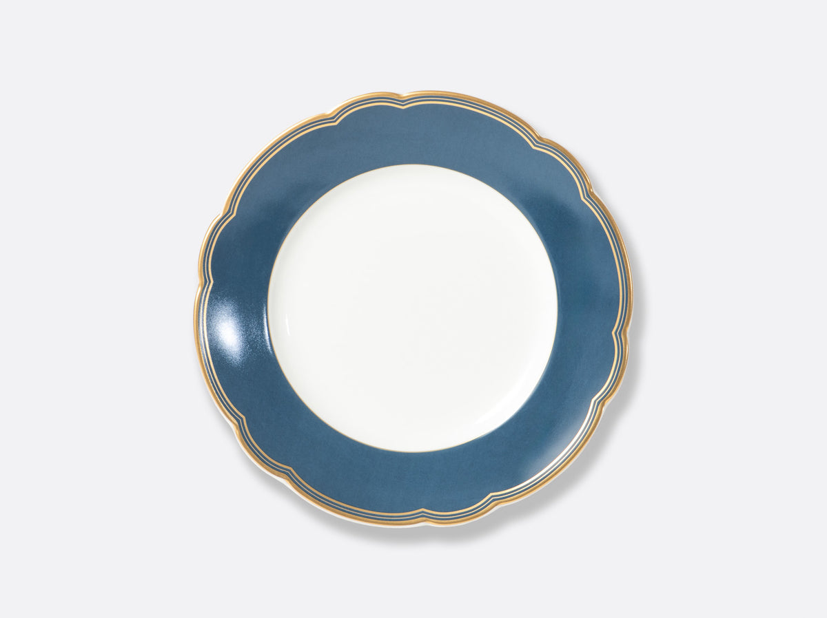 The Pompadour by Bernardaud is a white plate featuring a scalloped navy blue rim and gold trim, inspired by classic Limoges dinnerware from France.