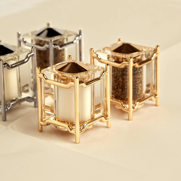 The Han Spice Jewels Set Salt & Pepper by L'Objet features four elegant, cube-shaped shakers with clear glass and 24k gold-plated or silver frames—beautifully arranged for gifting in a luxury box.