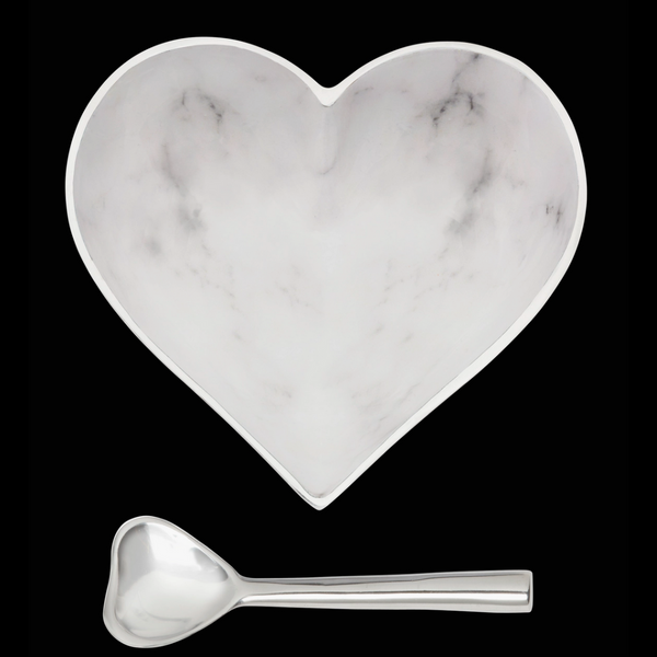The Inspired Generations Happy Heart Bowl With Spoon in White Marble, featuring subtle gray veining and a shiny metallic rim and handle, is shown against a black background. Both handcrafted pieces are part of the Happy Heart Bowls collection.