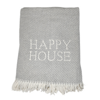 The Happy House Throw by A Soft Idea is a folded, light gray woven throw with white fringe and "HAPPY HOUSE" embroidered in large white letters; exclusive for home, and machine washable for easy care.