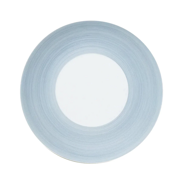 A round, white plate from the JL Coquet Hemisphere Dinnerware Storm Blue collection with a wide, storm blue rim featuring subtle circular lines, viewed from above on a plain white background.