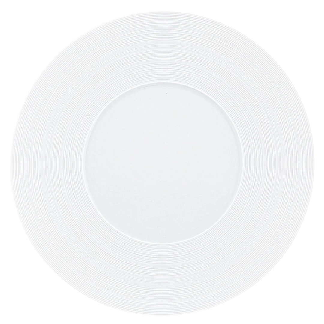 A JL Coquet Hemisphere Dinnerware Satin White plate, viewed from above, features a subtle circular textured pattern engraved on its porcelain rim.