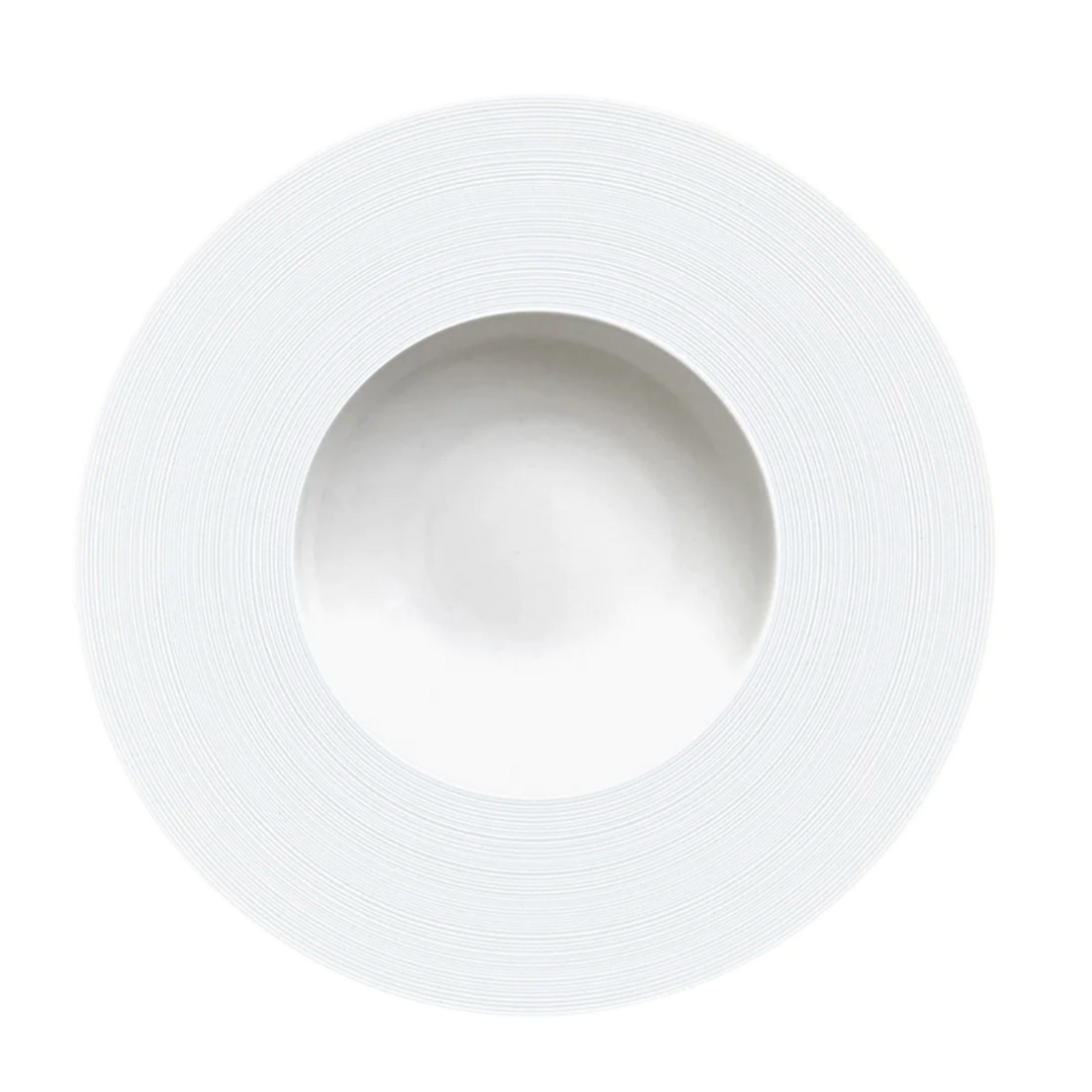 The JL Coquet Hemisphere Dinnerware Satin White is a round ceramic plate with a wide, textured rim and shallow center, showcasing minimalist engraved porcelain design from the Hemisphere collection on a white background.