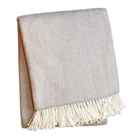 A Soft Idea's Herringbone Plush Throw in beige, with a subtle herringbone pattern and white fringed tassels along one edge, is folded against a plain white background. This cozy blanket is perfect for any space.