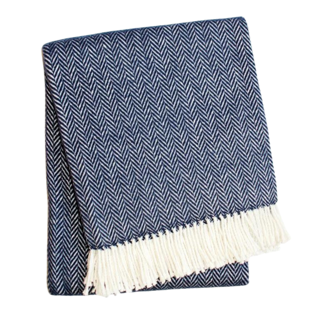 The Herringbone Plush Throw by A Soft Idea features a folded navy blue and white herringbone pattern with white fringe, is soft to the touch, machine washable, and shown against a white background.