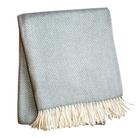 The A Soft Idea Herringbone Plush Throw features folded light blue and white herringbone design with fringed edges. This soft, machine washable blanket is perfect for cozy nights.