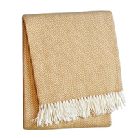 The A Soft Idea Herringbone Plush Throw in mustard yellow features a subtle herringbone pattern and white fringe. This soft, machine washable blanket is folded and shown against a plain white background.